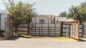 Un espace clos, avec un bâtiment en arrière-plan, un arbre et un sol recouvert de gravier.