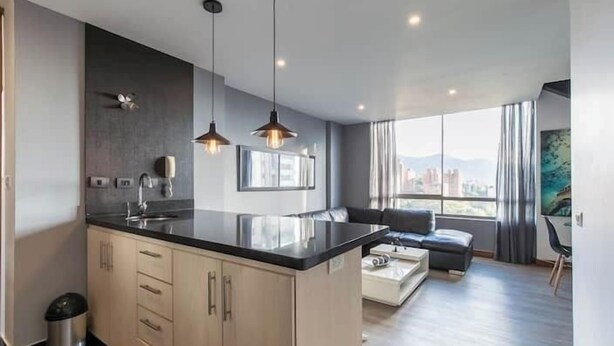 A modern kitchen with a large island, pendant lighting, and a view of the city. - Apartamentos SETAI (Medellín)