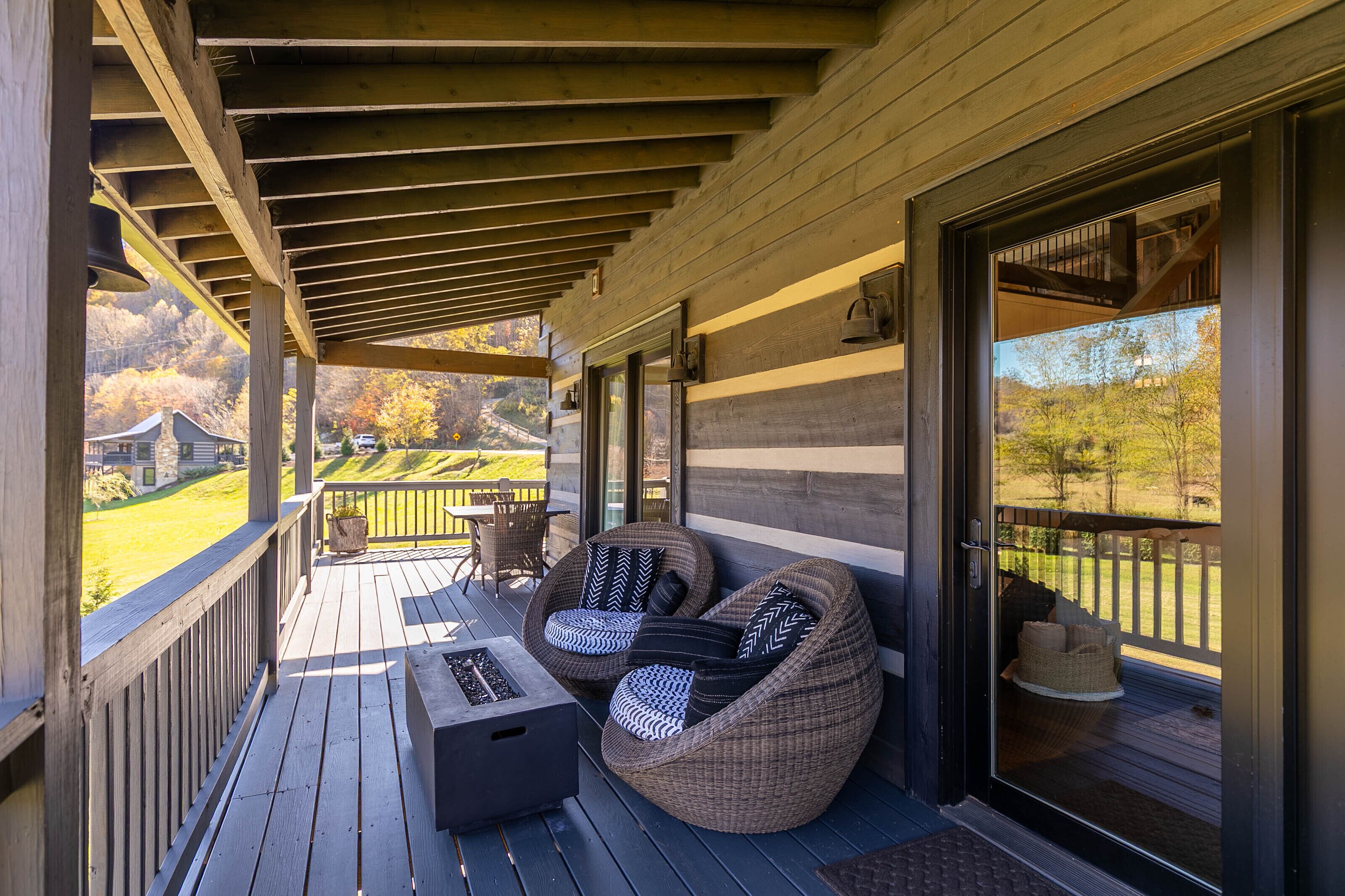 Une terrasse extérieure couverte, aménagée avec des meubles en osier et dotée d’un foyer.
