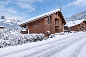 Eine Holzhütte mit schneebedecktem Dach, einem Schild mit der Aufschrift 'Chalet du Ruisseau' und einer Seilbahn im Hintergrund.