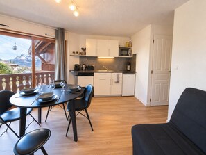 A compact kitchen with white cabinets, a microwave, and a dining area with a table set for four.