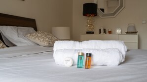 A neatly made bed with white linens, a set of towels, and two toiletry bottles on a bedside table. - Appartement Trocadero - 4 étoiles - Welkeys (Paris)