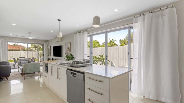 A modern kitchen with a large island, white cabinetry, and a view of the backyard. - Spacious 4-Bed House with Secure Parking (Northgate)