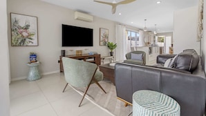 A modern living room with a flat-screen TV, a ceiling fan, and a sofa. - Spacious 4-Bed House with Secure Parking (Northgate)