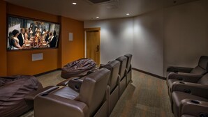 Een bioscoopzaal met luxe fauteuils, een kruipzak en een groot scherm waarop een film te zien is.