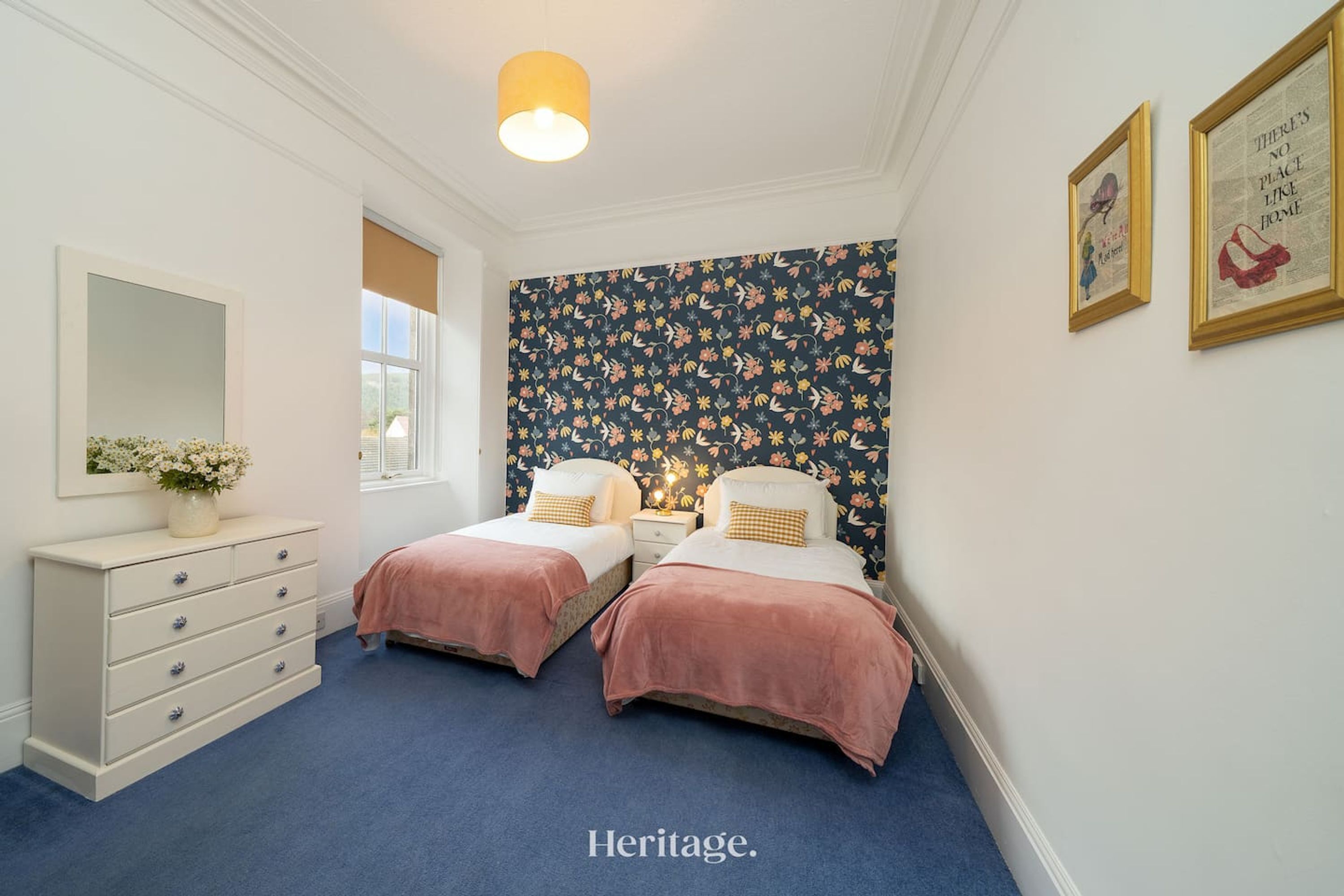 A bedroom with two beds, a dresser, a mirror, and a window.