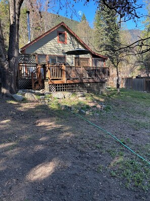 A cabin with a porch, a chimney, and a view of trees and mountains.