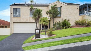 A two-story house with a garage, a well-maintained lawn, and a mailbox. - Pacific View - Pet Friendly (Flinders)