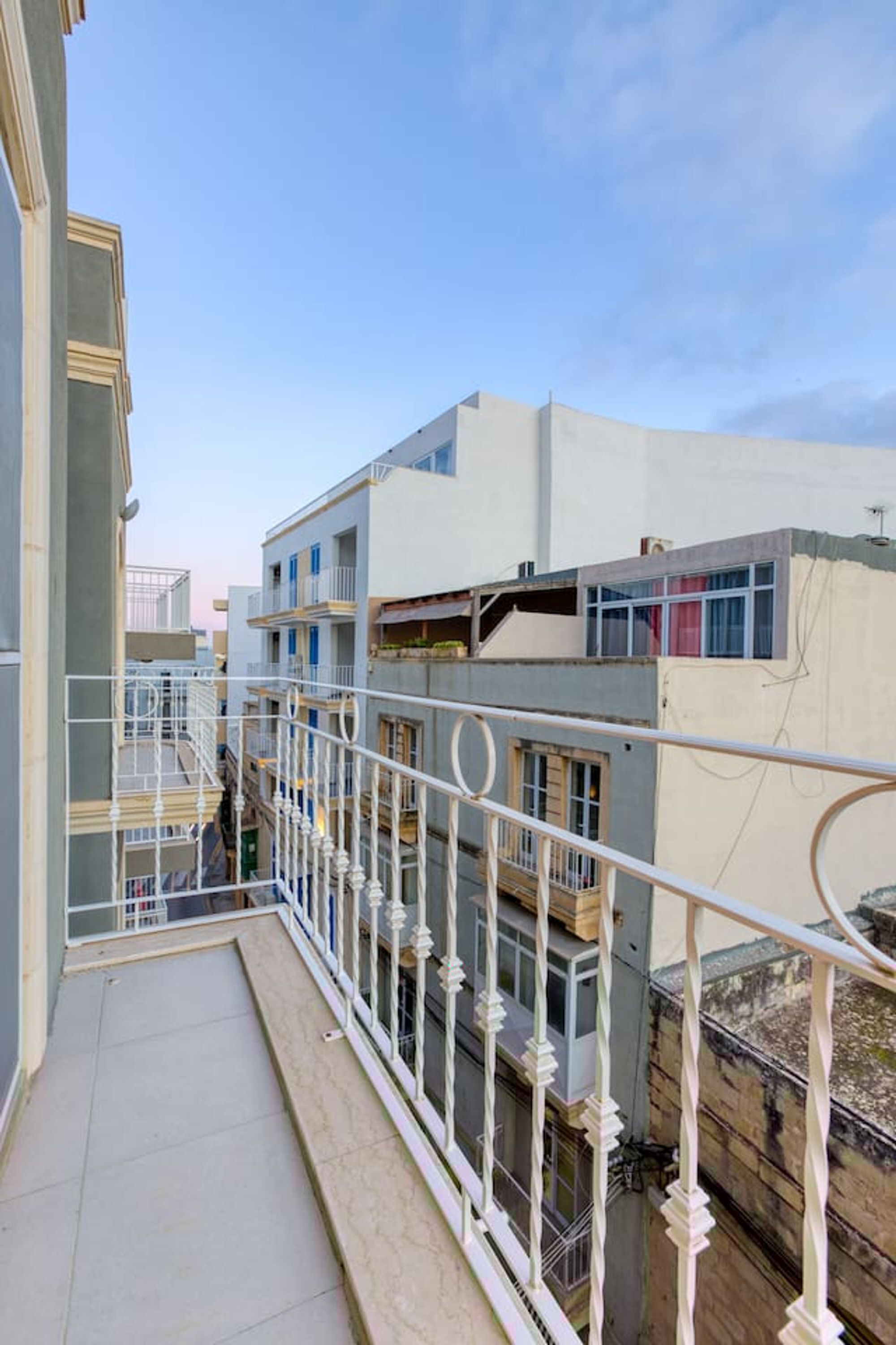 Un balcone con ringhiere bianche che si affaccia su una zona residenziale con diversi edifici.