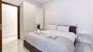 A modern bedroom with a large bed, a wardrobe, a bedside table, and a mirror. - Valley Sea Views With Furnished BBQ Balcony (St. Julian's)