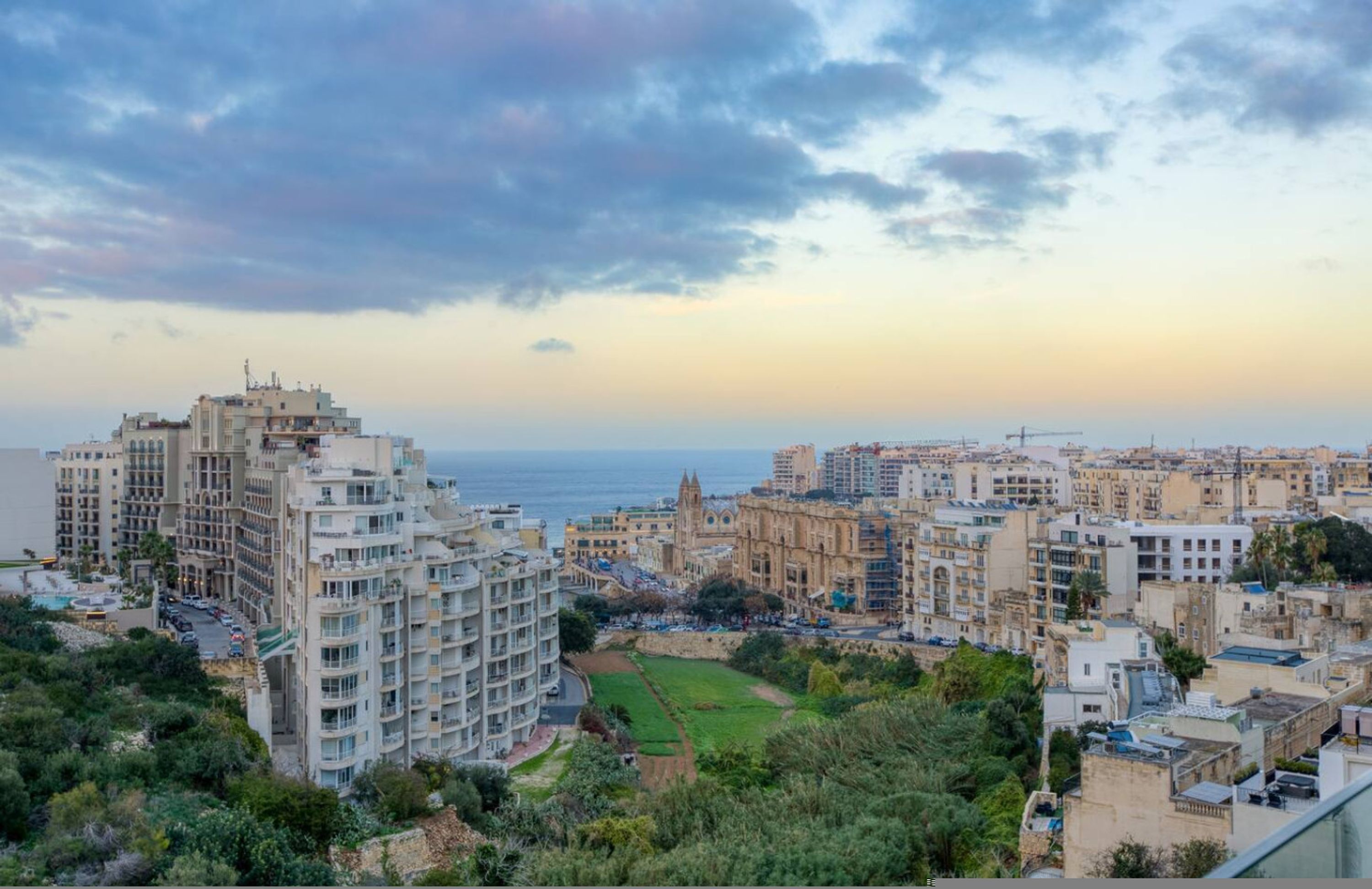 Paisatge urbà costaner amb una combinació d'edificis moderns i històrics, una església destacada i vista al mar.