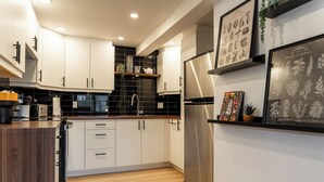 Een moderne keuken met witte kasten, een roestvrijstalen koelkast en een zwarte backsplash.
