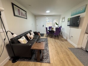 A living room with a sofa, coffee table, and dining area with chairs. - Luxe 2BD Suite/Sweet Spot in South Surrey (Surrey)