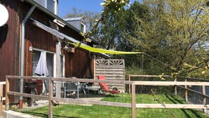 Un patio trasero con una terraza de madera, una cerca metálica y un césped.