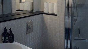 A bathroom with a white toilet, a sink, and a mirror. There are two bottles of soap on the sink. - Cozy flat in Marylebone (London)