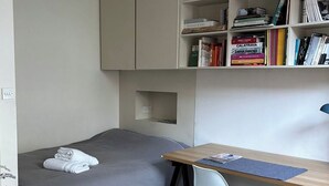 A small, neatly organized room with a bed, a desk, and a bookshelf. - Cozy flat in Marylebone (London)