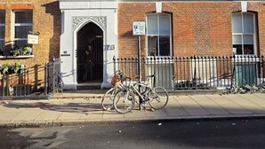 A brick building with a large arched entrance, a sign for The Bloxworth Hotel, and a bicycle parked in front. - Cozy flat in Marylebone (London)