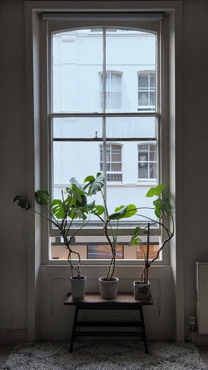 Een raam met drie plantenpotten op een klein tafeltje.