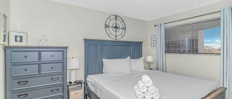 A bedroom with a bed, dresser, nightstand, lamp, and a compass wall decoration.
