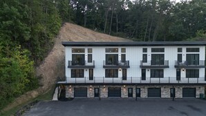 Um edifício moderno de dois andares com telhado plano, várias varandas e fachada de pedra.