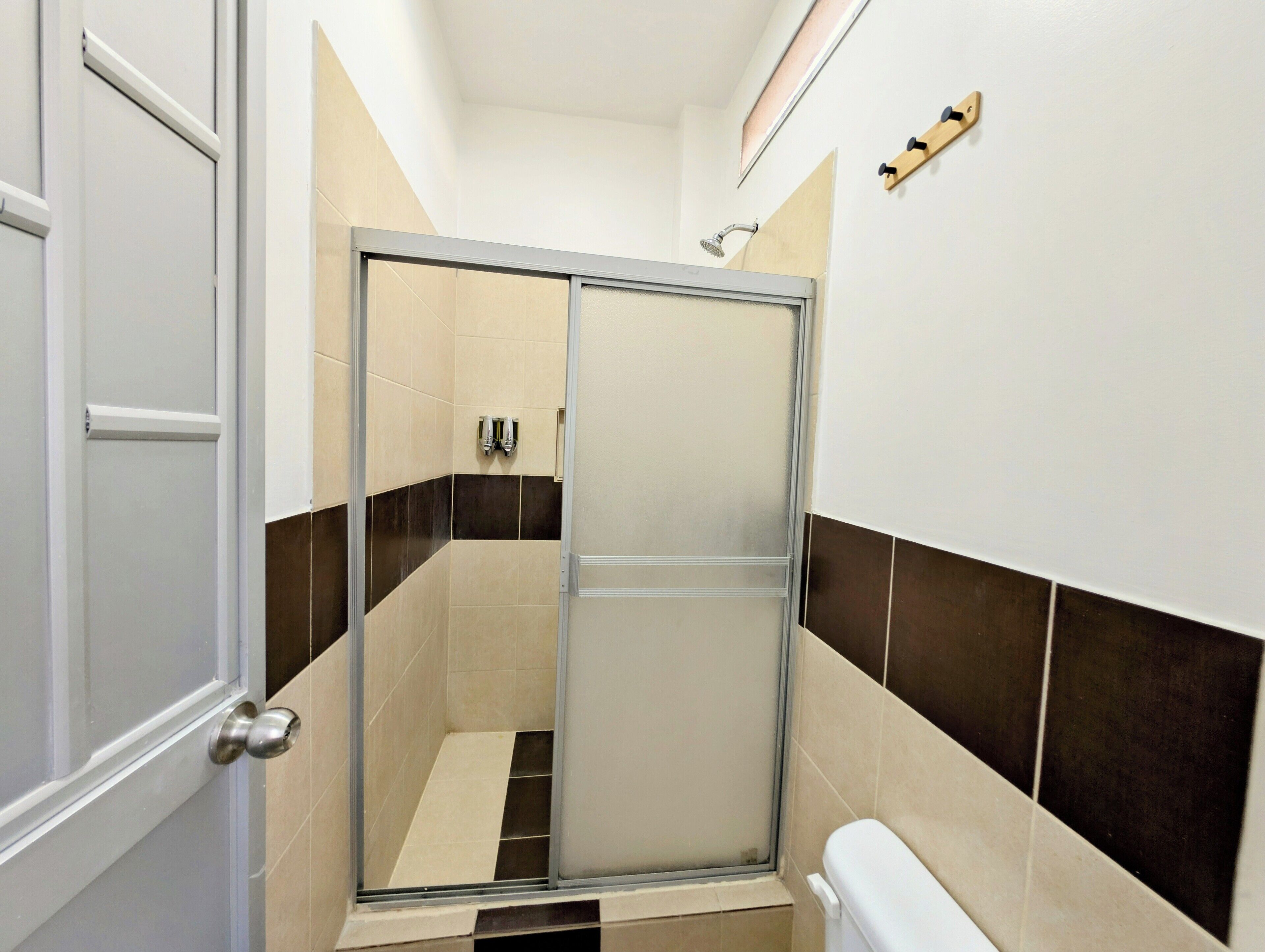 Et moderne badeværelse med en glasbrusekabine, toilet og håndklædestang.