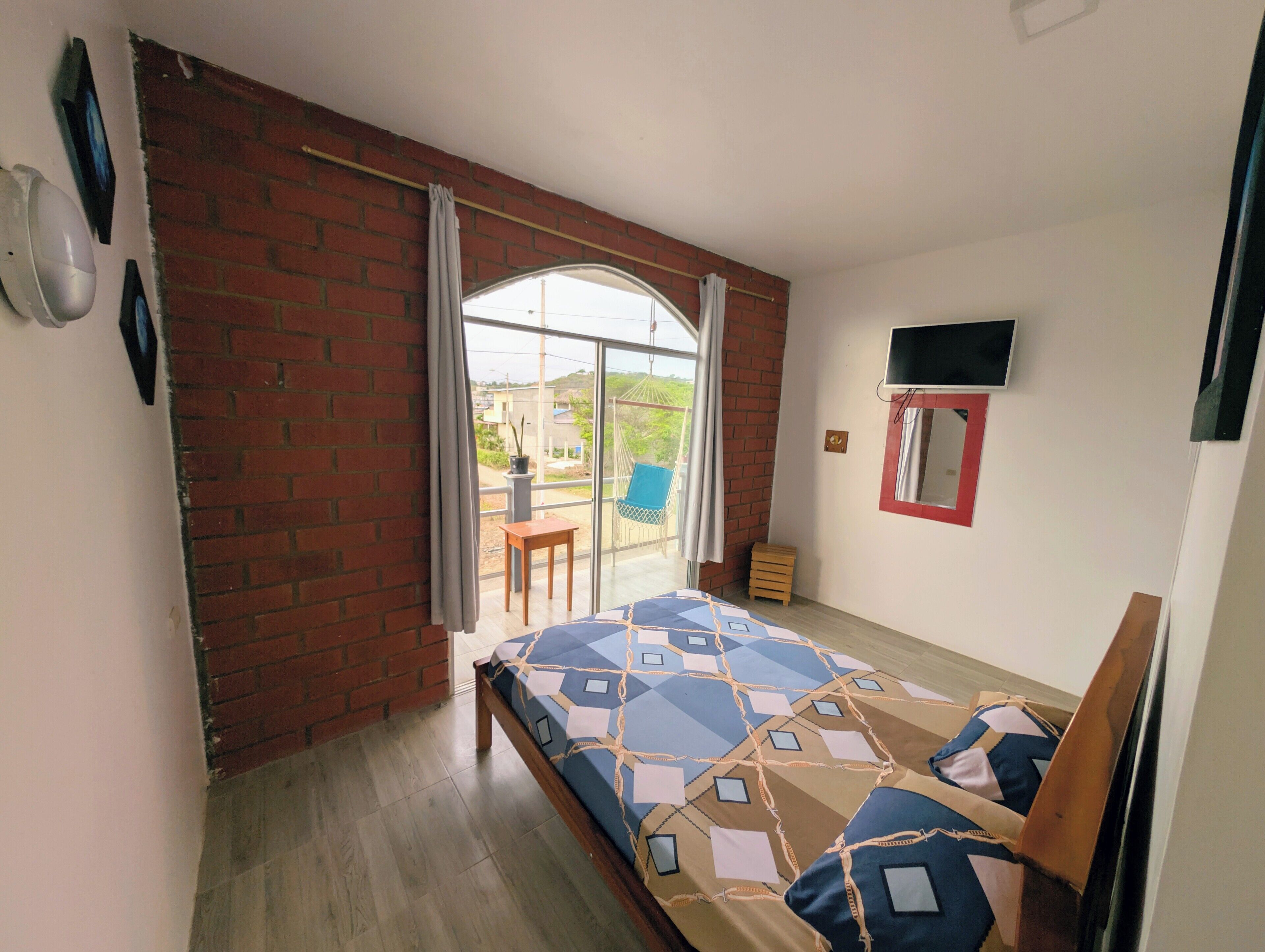 Un dormitorio con cama, televisión, ventana y vistas al exterior.