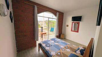 Un dormitorio con cama, televisión, ventana y vistas al exterior.