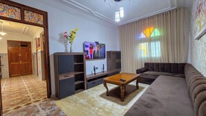 Un salon comprenant un canapé, un téléviseur, un meuble en bois et un vase décoratif.