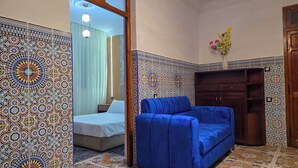 Une pièce avec un lit, un canapé bleu, une armoire en bois et des murs à motifs.