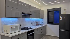 Une cuisine moderne avec des meubles gris, un four à micro-ondes, une cuisinière et un réfrigérateur noir.