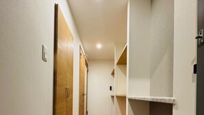 Un pasillo estrecho con suelo de madera, paredes blancas y suelo de baldosas al final.
