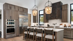 Una cocina moderna con armarios de madera oscura, electrodomésticos de acero inoxidable y una isla central con taburetes de bar.