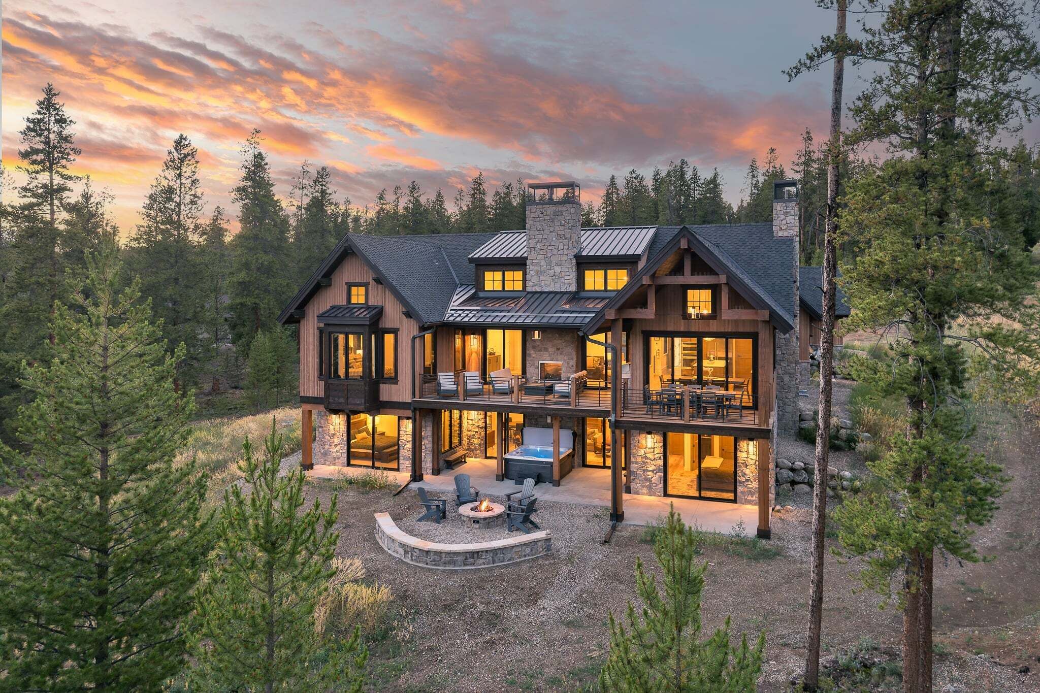 A two-story house with a stone fireplace, outdoor seating, and a deck.