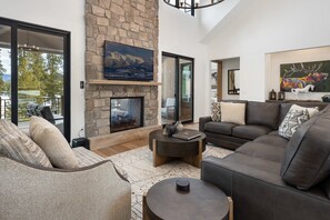 A modern living room with a stone fireplace, comfortable seating, and artwork on the walls. - Pole Creek Home 739 I Great Views I Private Hot Tub I Bunks I Game Room I Discounted Attractions (Tabernash)