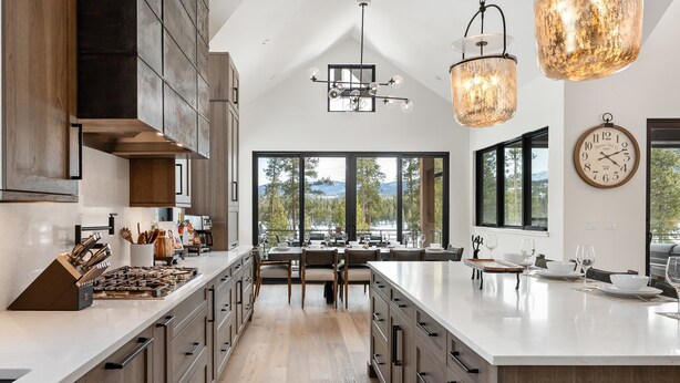 Una cocina moderna con una isla grande, armarios de madera y vistas a un lago a través de amplios ventanales.