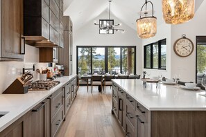 Une cuisine moderne dotée d’un grand îlot central, de meubles en bois et offrant une vue sur un lac grâce à de grandes fenêtres.