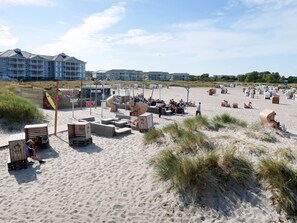 En strand med strandstolar och parasoller, ett livräddartorn och byggnader i bakgrunden.