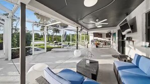 Eine großzügige Außenveranda mit moderner Möbel, einem Deckenventilator und Blick auf den Garten.