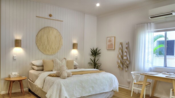 Ein Schlafzimmer mit Bett, Nachttischen, einem Schreibtisch und einem Fenster.