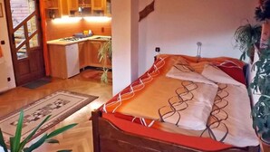 Un dormitorio con cama de madera, una pequeña cocina con armarios de madera y vistas al exterior.