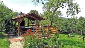 Una estructura de madera rústica con techo inclinado, un sendero de piedra que conduce a ella y una valla de madera alrededor del área.