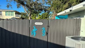 Une porte en bois avec une pancarte indiquant « BIENVENUE » et des motifs décoratifs représentant des tortues et des hippocampes.