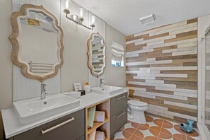 Ein modernes Badezimmer mit zwei Waschbecken, einer Toilette und einer Duschkabine.