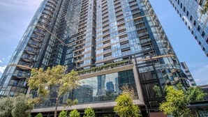 A high-rise building with a curved facade, multiple balconies, and a glass entrance. - Luxe 2BR Escape | City View, Pool & Gym (Docklands)