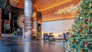 A lobby with a large Christmas tree, seating area, and a modern design with wooden accents and a large clock. - Luxe 2BR Escape | City View, Pool & Gym (Docklands)
