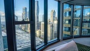 A high-rise hotel room with large windows offering a cityscape view. - Luxe 2BR Escape | City View, Pool & Gym (Docklands)