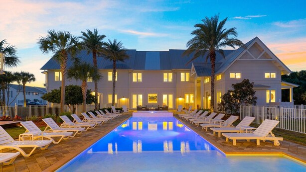 A hotel with a swimming pool, lounge chairs, and palm trees. - NEW: Destin's Premier Wedding & Corporate Retreat | Outdoor Pavilion | Resort Pool (Miramar Beach)