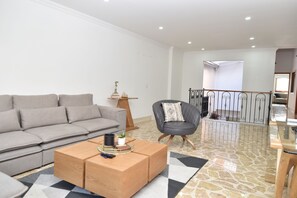 A modern living room with a grey sofa, a wooden coffee table, and a grey armchair.