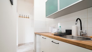 A modern kitchen with a wooden countertop, stainless steel sink, and white cabinets. - Saska Kępa Lavish Studio (Warszawa)