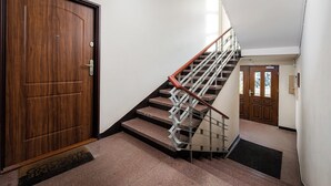 A wooden door, a staircase with metal railings, and a carpeted landing. - Saska Kępa Lavish Studio (Warszawa)